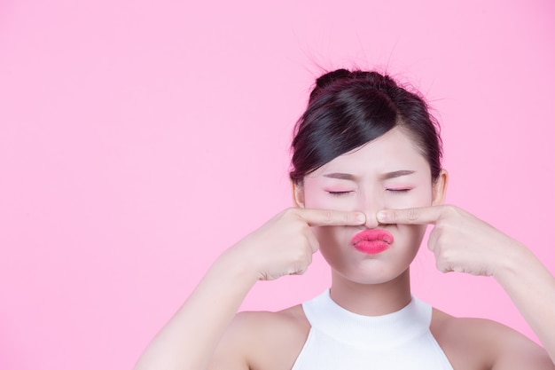 Donne facciali di problemi della pelle - giovani donne infelici che toccano la sua pelle su un fondo rosa.