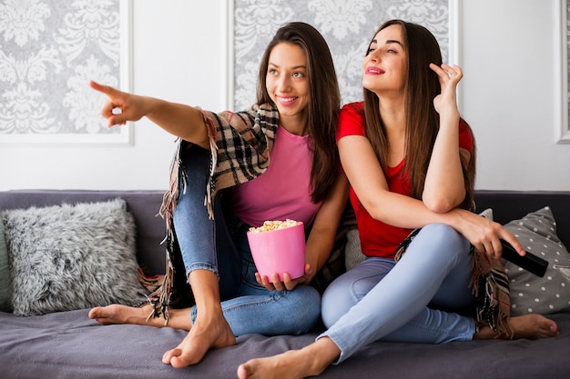 Donne felici a casa che mangiano popcorn