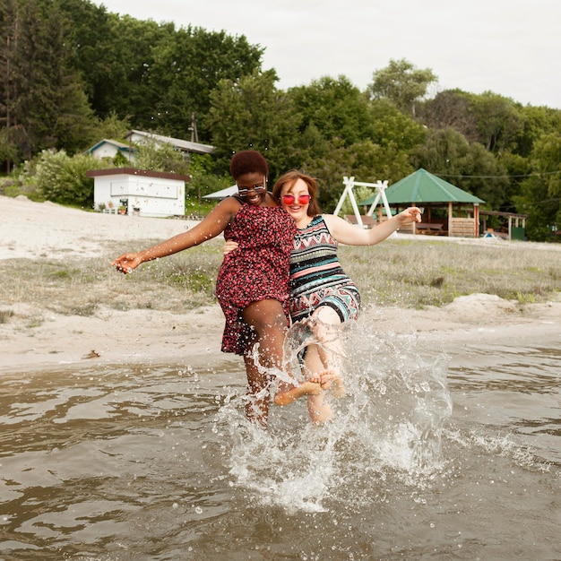 Donne felici che giocano con l'acqua in spiaggia