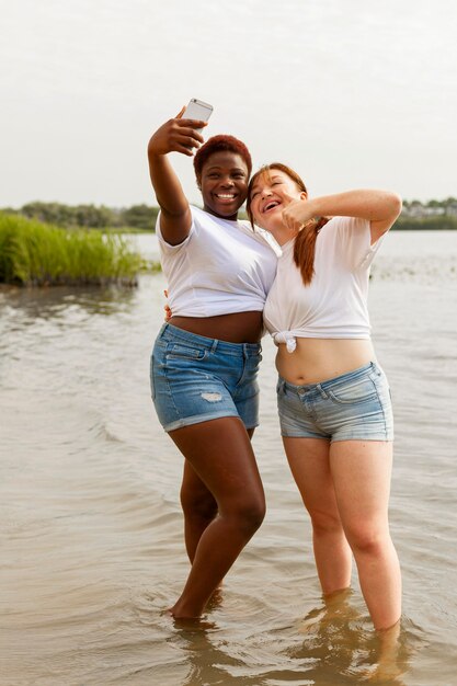 Donne felici che prendono selfie in spiaggia