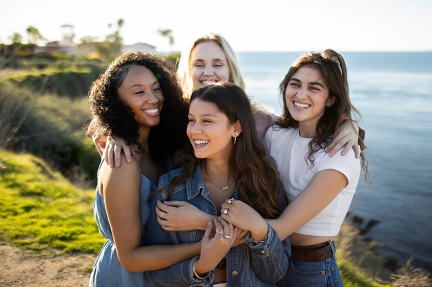 Donne felici del colpo medio che posano al mare