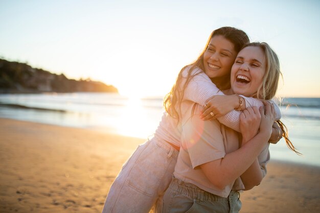 Donne felici del colpo medio che si abbracciano in spiaggia