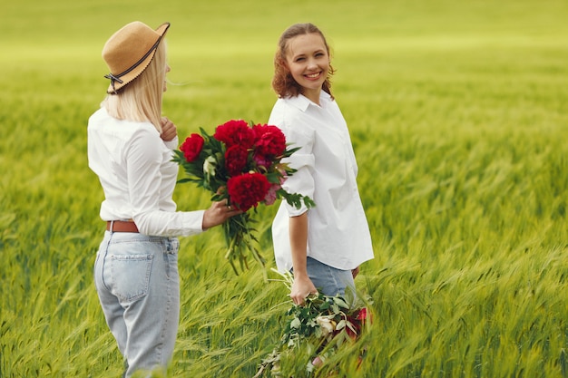 Donne in abiti eleganti in piedi in un campo estivo