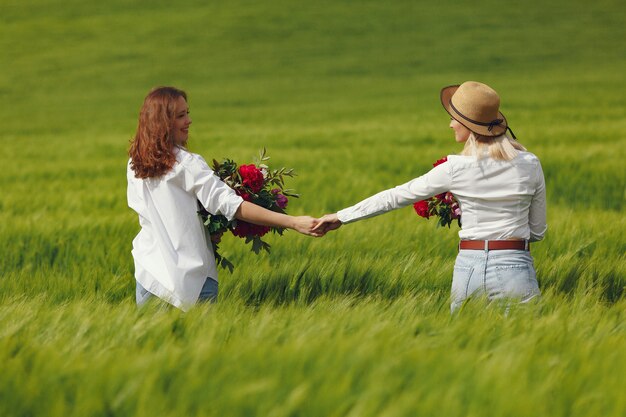 Donne in abiti eleganti in piedi in un campo estivo