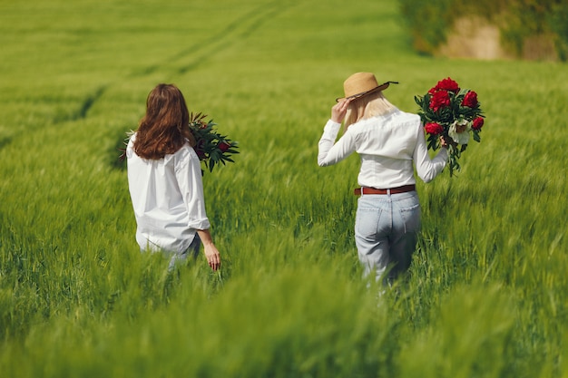 Donne in abiti eleganti in piedi in un campo estivo