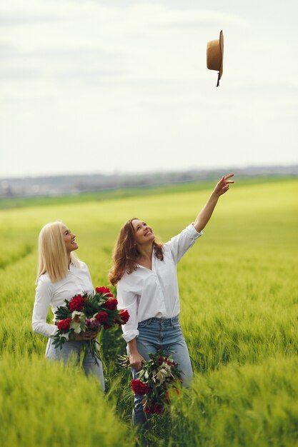 Donne in abiti eleganti in piedi in un campo estivo