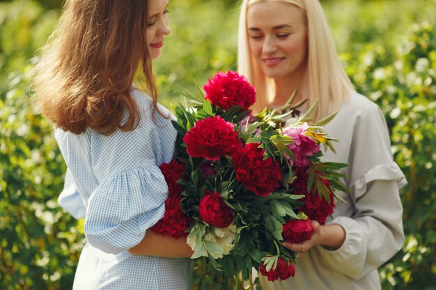 Donne in abiti eleganti in piedi in un campo estivo