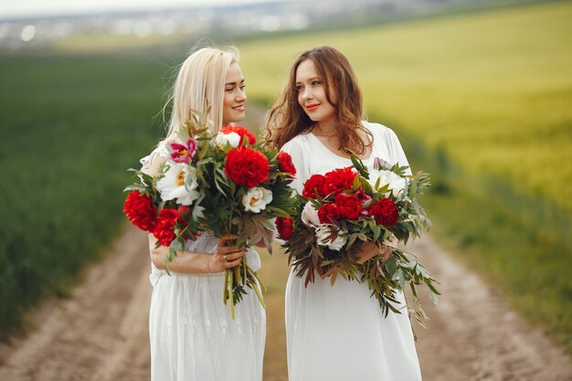 Donne in abito elegante in piedi in un campo estivo