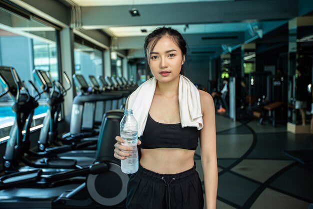 Donne in piedi e rilassanti dopo l'esercizio, con in mano una bottiglia d'acqua.