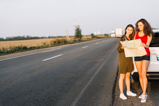 Donne in piedi vicino a macchina bianca con mappa