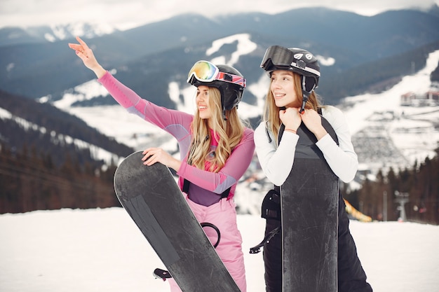 Donne in tuta da snowboard. Sportive su una montagna con uno snowboard in mano all'orizzonte. Concetto di sport