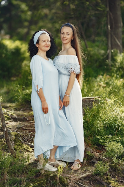 Donne in una foresta estiva. Signora in un vestito blu. Famiglia in posa e abbraccio.