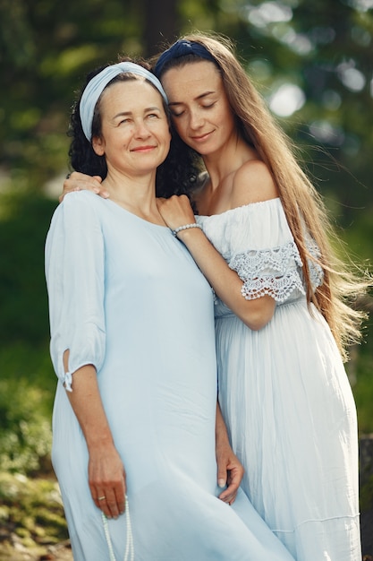 Donne in una foresta estiva. Signora in un vestito blu. Famiglia in posa e abbraccio.