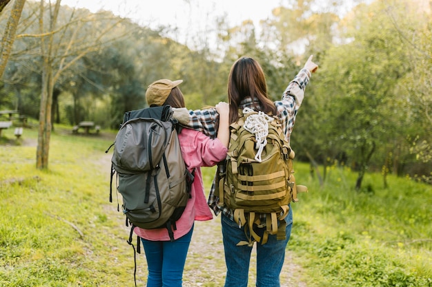 Donne irriconoscibili con zaini che puntano a distanza