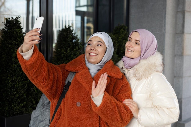 Donne musulmane con l'hijab che si fanno un selfie e salutano mentre sono in vacanza