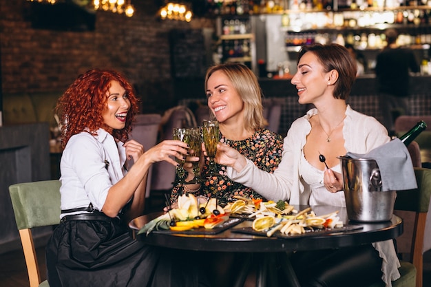 Donne nel bar che bevono cocktail chiacchieranti