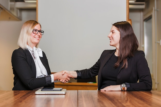 Donne sedute al tavolo stringendo la mano sorridente