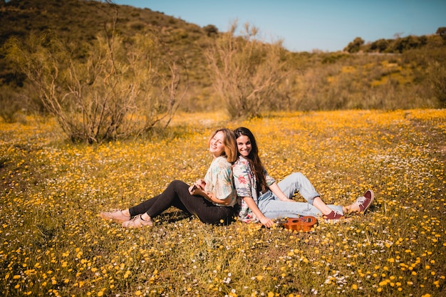 Donne sorridenti che giocano ukulele nel campo