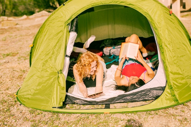 Donne sorridenti che leggono i libri in tenda