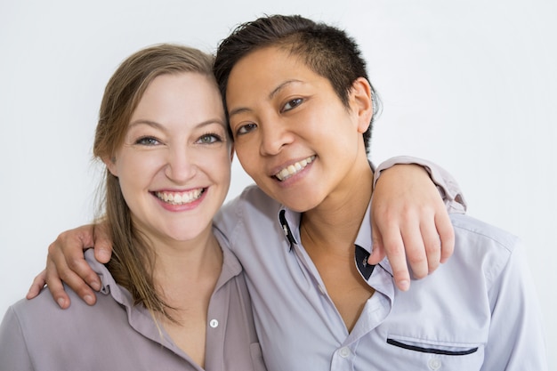 Donne sorridenti che si abbracciano e che posano alla macchina fotografica