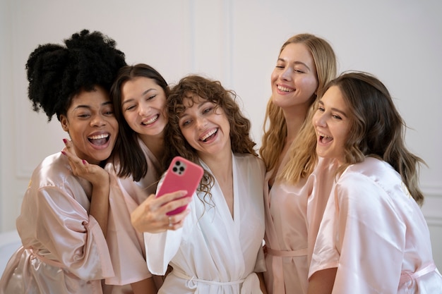 Donne sorridenti del colpo medio che prendono selfie