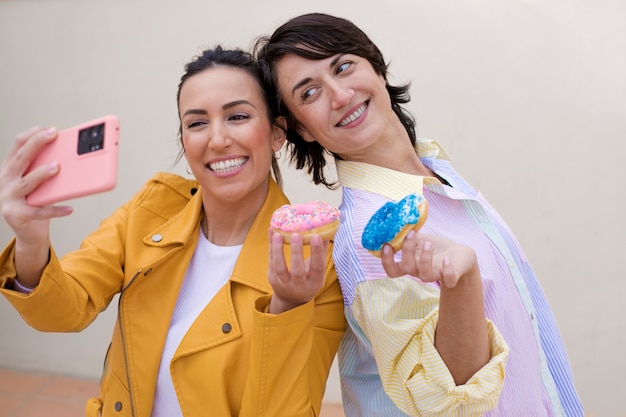 Donne sorridenti del colpo medio che prendono selfie