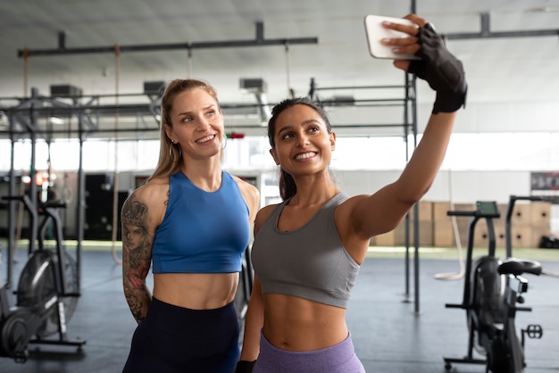 Donne sorridenti del colpo medio che prendono selfie