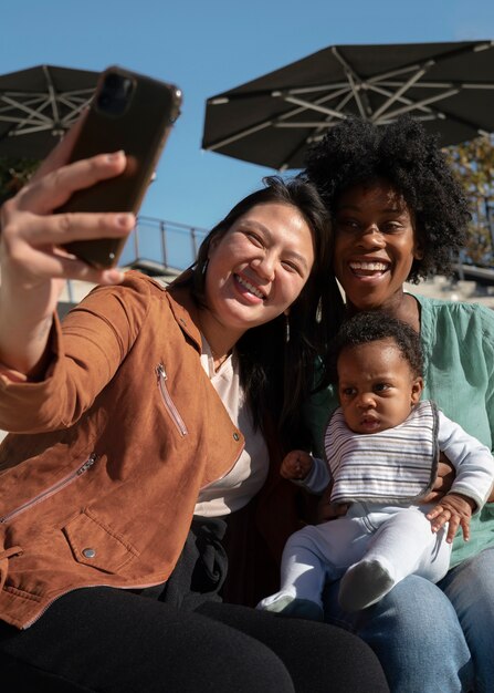 Donne sorridenti del colpo medio che prendono selfie