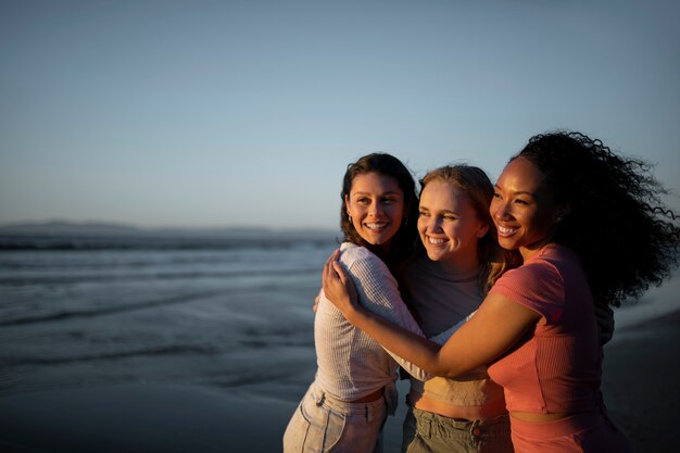 Donne sorridenti del colpo medio che si abbracciano in riva al mare