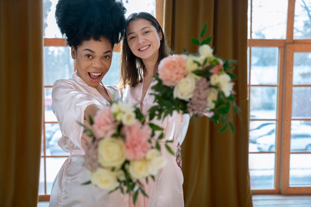 Donne sorridenti del colpo medio che tengono i fiori