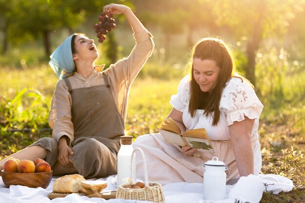 Donne sorridenti del colpo pieno che si siedono all'aperto