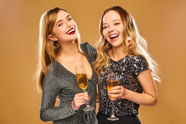 Donne sorridenti felici in eleganti abiti glamour con bicchieri di champagne