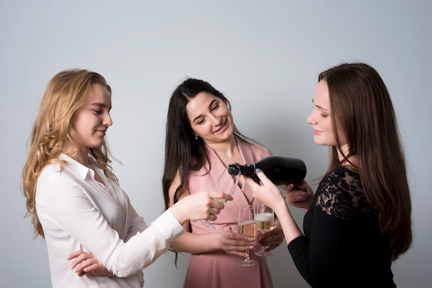 Donne sorridenti operate che versano champagne