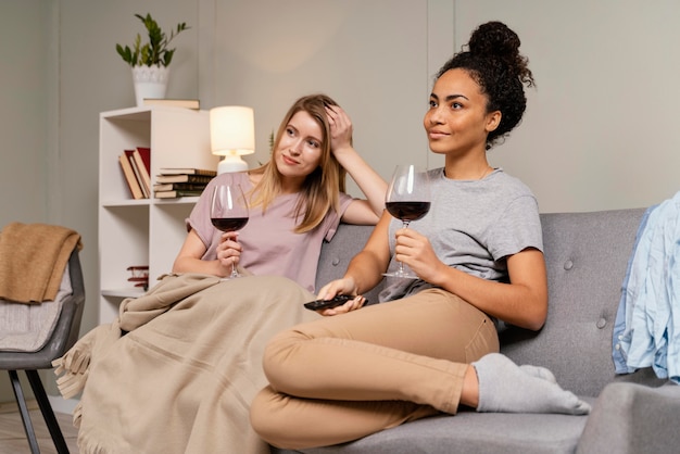 Donne sul divano a guardare la tv e bere vino