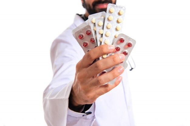 Dottore holding pillole su sfondo bianco