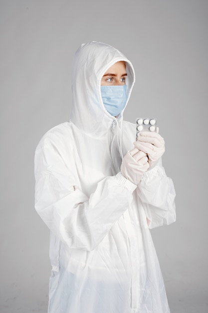 Dottore in una maschera medica. Tema Coronavirus. Isolato sopra il muro bianco. Donna con le pillole.