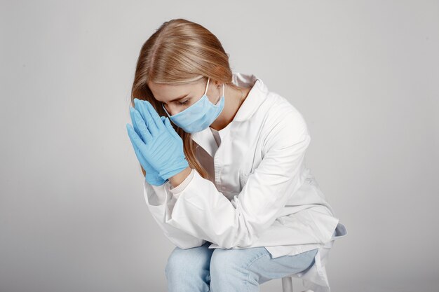 Dottore in una maschera medica. Tema Coronavirus. Isolato sopra il muro bianco. Pregate per i dottori.