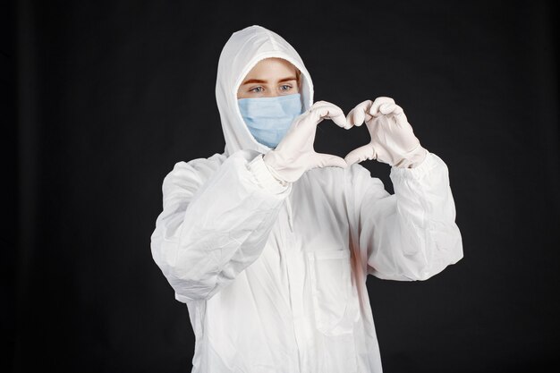 Dottore in una maschera medica. Tema Coronavirus. Isolato sopra il muro nero. Donna in una tuta protettiva.