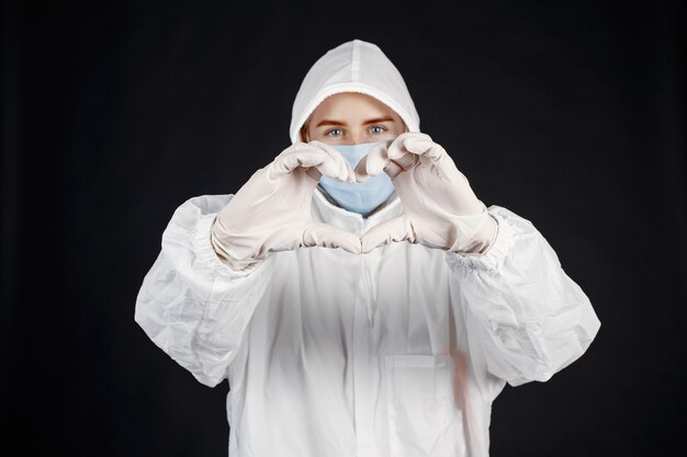Dottore in una maschera medica. Tema Coronavirus. Isolato sopra il muro nero. Donna in una tuta protettiva.