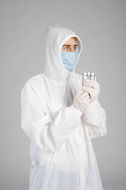 Dottore in una maschera medica. Tema Coronavirus. Isolato su sfondo bianco. Donna con le pillole.