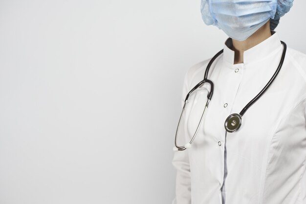 Dottore in uniforme bianca e maschera per il viso con uno stetoscopio