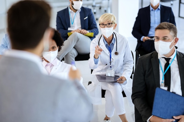 Dottoressa che parla con il presentatore mentre partecipa a un seminario durante l'epidemia di coronavirus