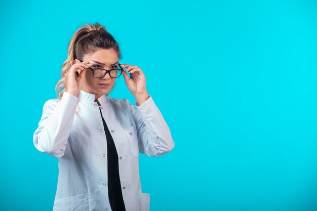 Dottoressa in uniforme bianca con gli occhiali da vista.