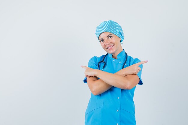 Dottoressa in uniforme blu che punta lontano e che sembra felice, vista frontale.