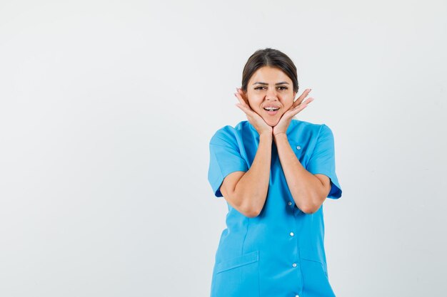 Dottoressa in uniforme blu che si fa i cuscini sulle mani e sembra carina