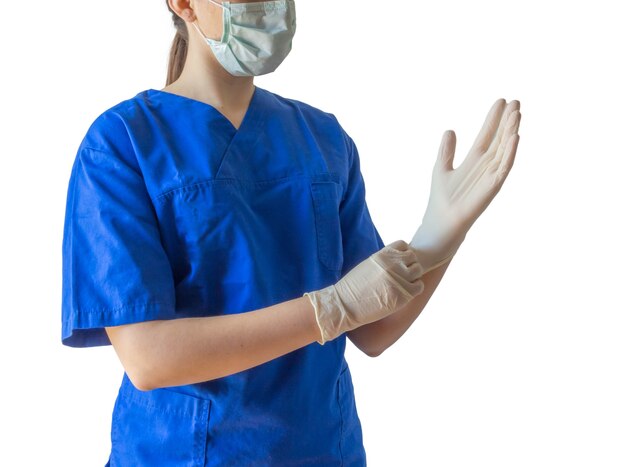 Dottoressa in uniforme medica e maschera che indossa guanti medicali che si prepara per un intervento chirurgico