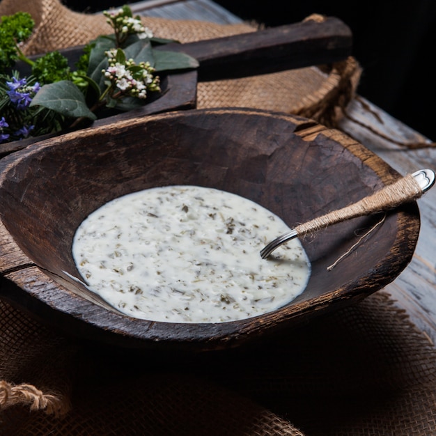 Dovga con fiori e cucchiaio nel piatto di legno