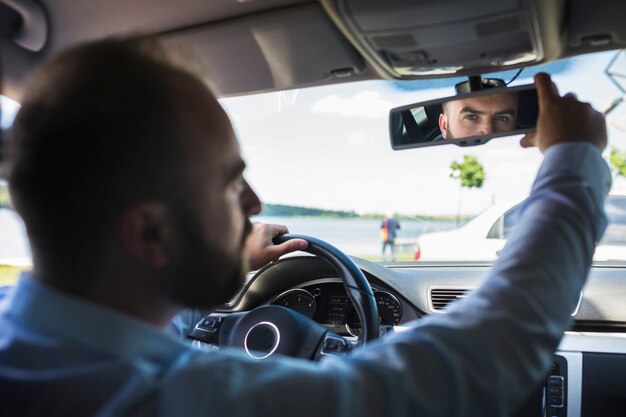 Driver maschio che regola lo specchietto retrovisore dell&#39;automobile
