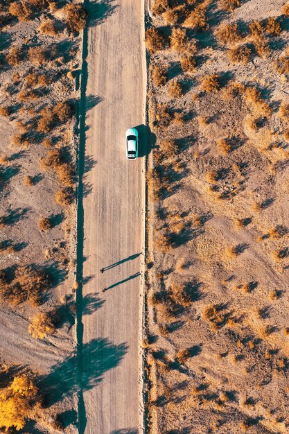 Drone aereo colpo di una stretta strada nel deserto con una macchina sul lato della strada