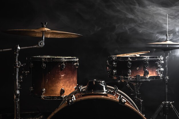 Drum kit su uno sfondo scuro con illuminazione scenica, copia spazio.